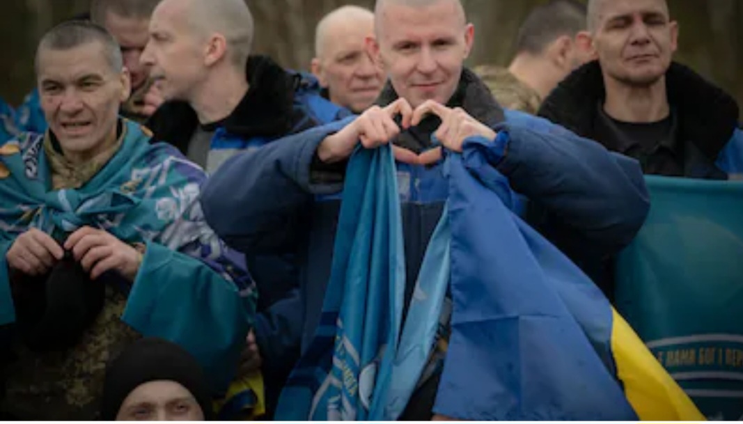 Ukrainian service members, draped in their national flags, celebrate their release from Russian captivity following a UAE-brokered prisoner exchange in April 2026